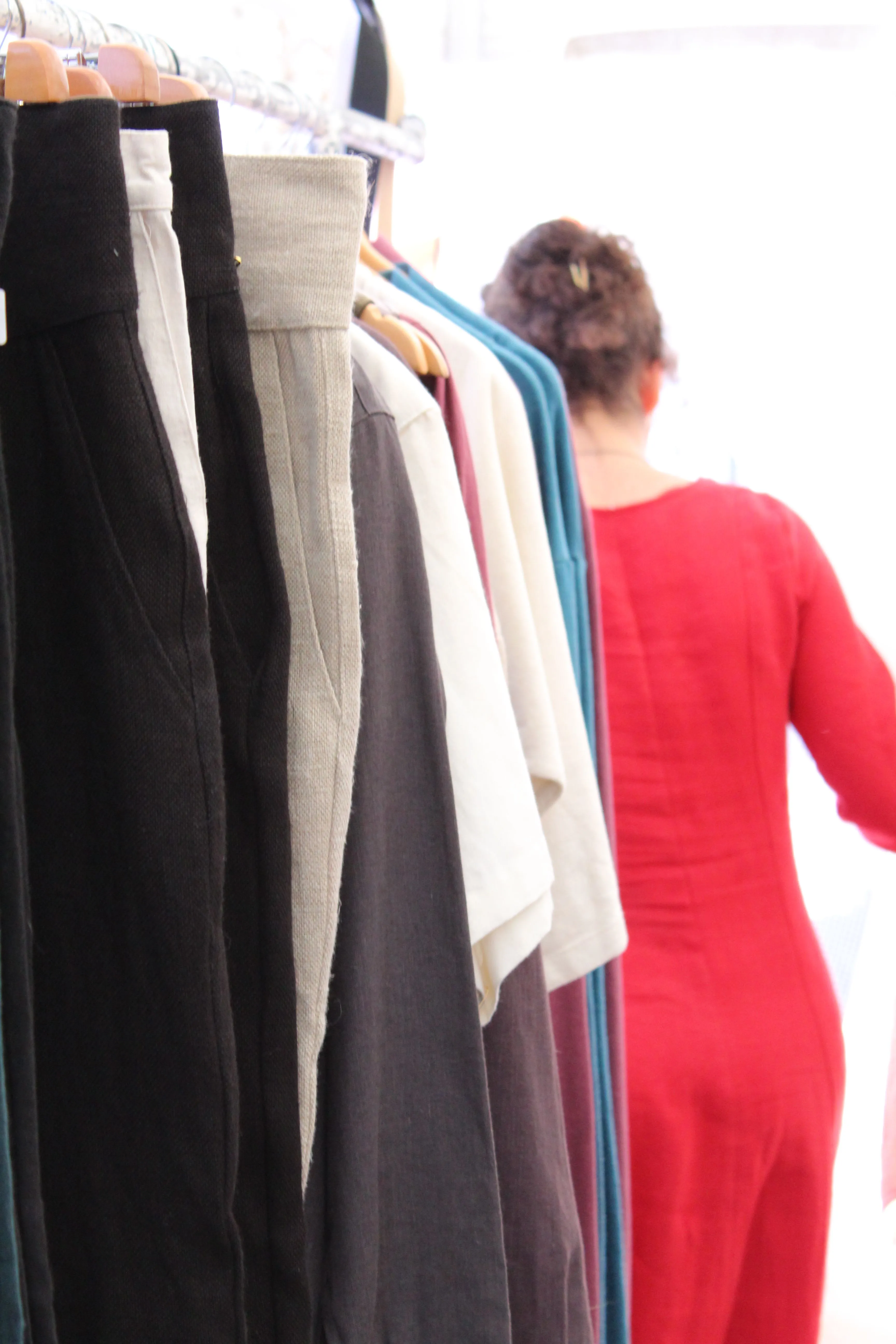 Portant de vêtements en lin cousus main, du noir à l'écru, et robe rouge ajustée portée de dos